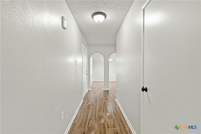 hall with hardwood / wood-style floors and a textured ceiling