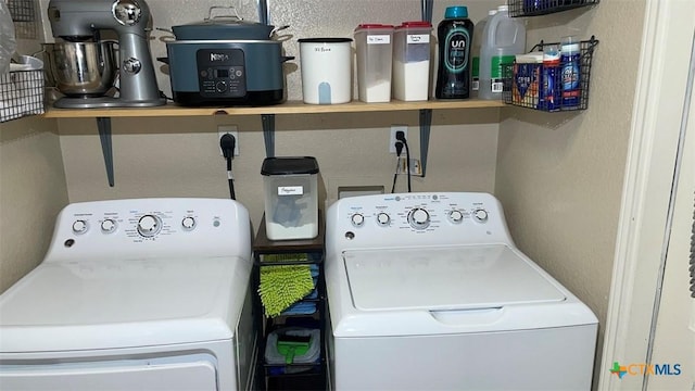 laundry room with a textured wall, washing machine and clothes dryer, and laundry area