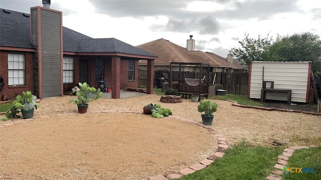 view of yard with an outdoor structure, a patio, a fire pit, and fence