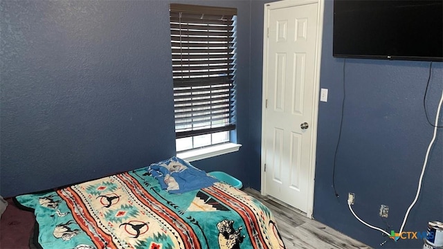 bedroom with a textured wall and wood finished floors