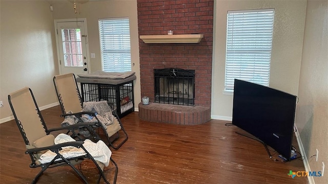 living room featuring wood finished floors, baseboards, and a brick fireplace