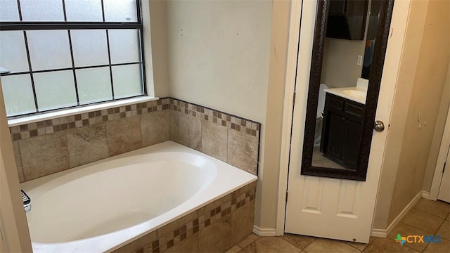 bathroom with tile patterned floors, baseboards, a garden tub, and vanity