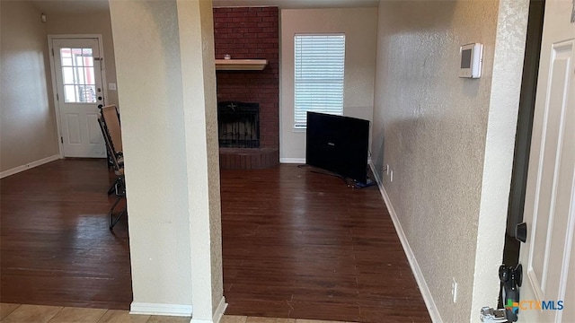 hallway featuring baseboards, wood finished floors, and a textured wall