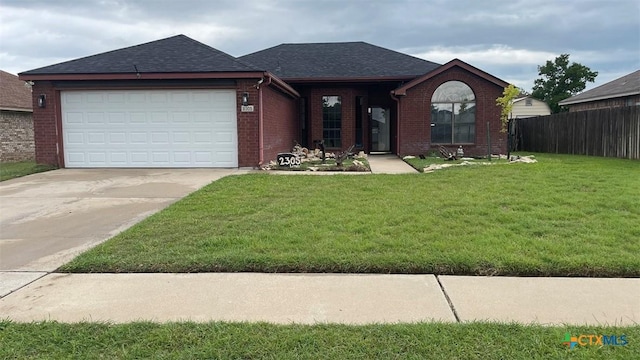 ranch-style house featuring a front lawn, brick siding, roof with shingles, concrete driveway, and fence