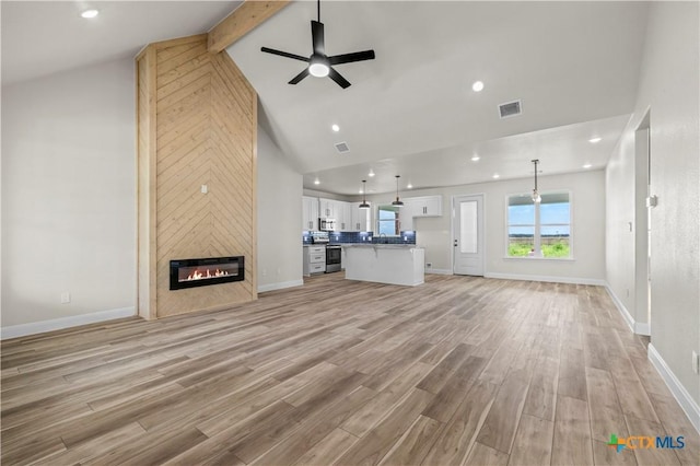 1811 Ember Dr, Temple, TX 76502 - unfurnished living room with beam ceiling, ceiling fan, a large fireplace, light wood-style flooring, and high vaulted ceiling