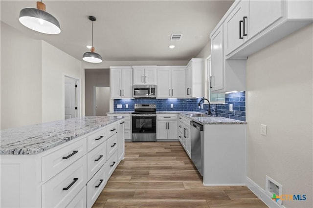 1811 Ember Dr, Temple, TX 76502 - kitchen featuring appliances with stainless steel finishes, tasteful backsplash, light wood finished floors, light stone countertops, and white cabinets