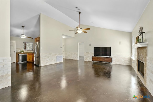 living room featuring concrete floors, a fireplace, visible vents, and a ceiling fan