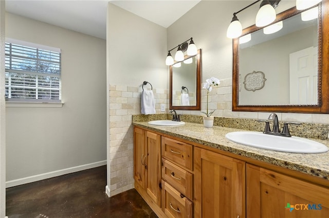 full bathroom featuring double vanity, finished concrete floors, baseboards, and a sink