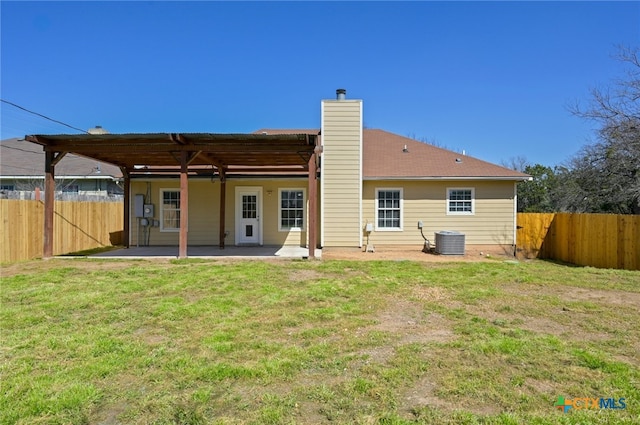 back of house with a yard, a chimney, a patio area, cooling unit, and a fenced backyard