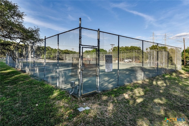 view of tennis court with a gate and fence