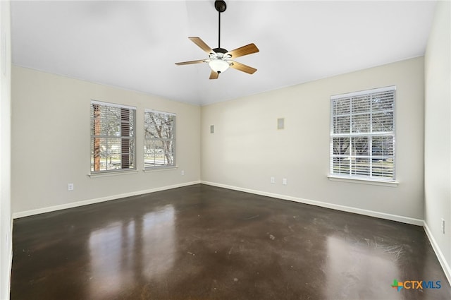 empty room featuring concrete flooring, vaulted ceiling, ceiling fan, and baseboards