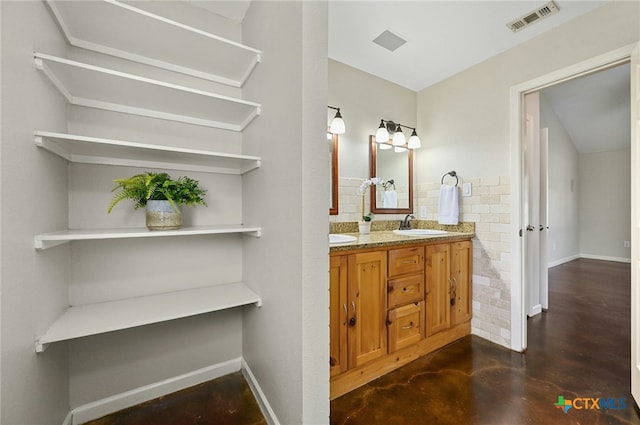 full bathroom with finished concrete flooring, double vanity, baseboards, visible vents, and a sink