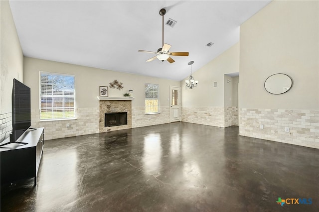 unfurnished living room featuring finished concrete flooring, visible vents, a fireplace, high vaulted ceiling, and ceiling fan with notable chandelier