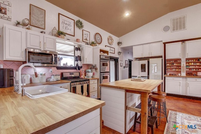 kitchen with visible vents, lofted ceiling, stainless steel appliances, wood counters, and a sink