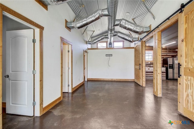 below grade area with stainless steel fridge with ice dispenser and baseboards