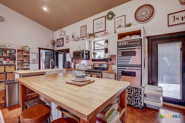 kitchen with stainless steel appliances, butcher block countertops, a sink, and open shelves