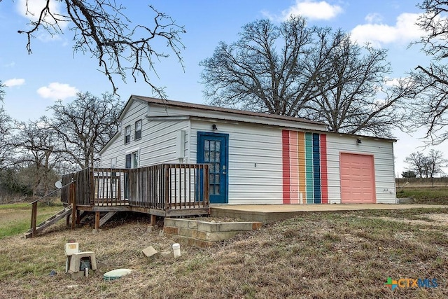 exterior space featuring a garage, an outbuilding, and a wooden deck