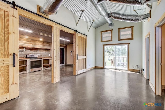 unfurnished living room with baseboards, a barn door, a towering ceiling, and finished concrete floors