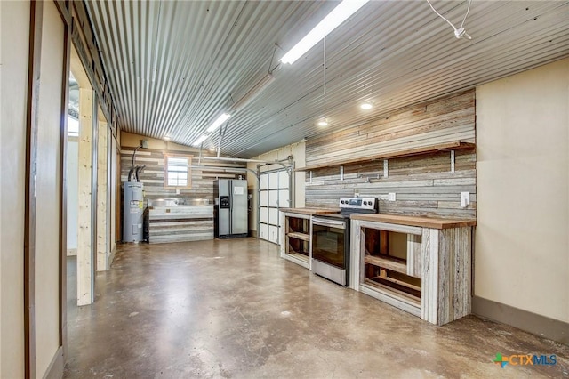 kitchen with stainless steel appliances, butcher block counters, finished concrete floors, open shelves, and electric water heater