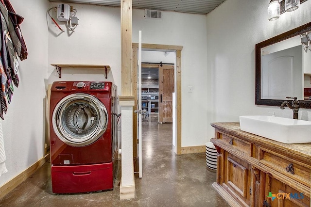 washroom featuring visible vents, baseboards, laundry area, washer / dryer, and a sink