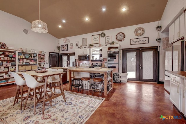 dining space with finished concrete flooring, recessed lighting, high vaulted ceiling, and french doors