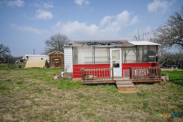 rear view of house with an outbuilding, a lawn, an exterior structure, and metal roof