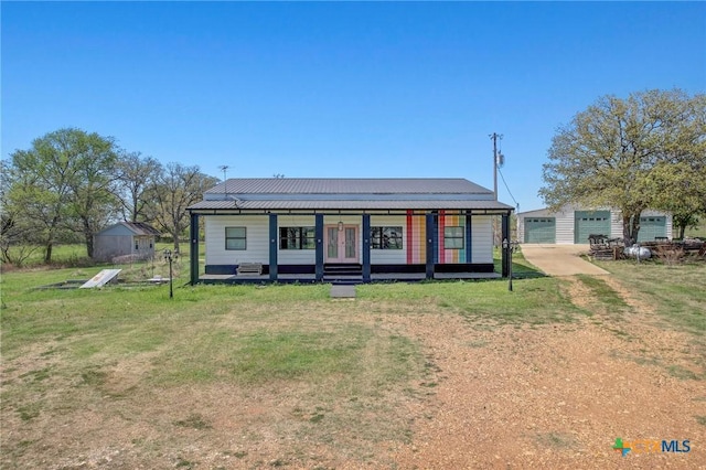 bungalow-style home with an outbuilding, metal roof, french doors, a front yard, and a garage