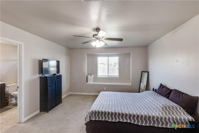 bedroom with baseboards, light carpet, ensuite bathroom, and a ceiling fan