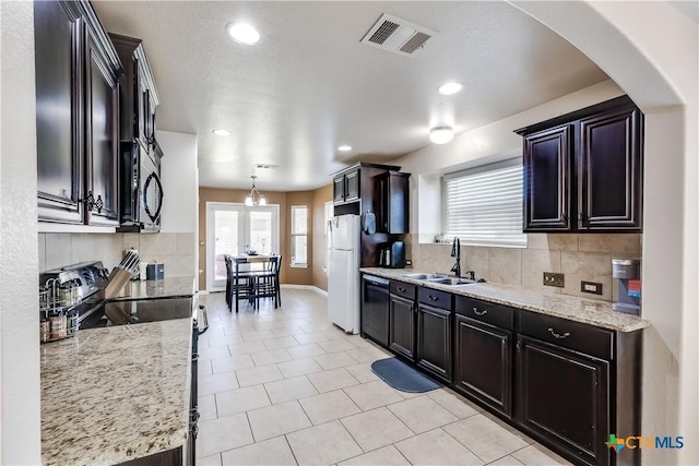 kitchen with black appliances, visible vents, backsplash, and a sink