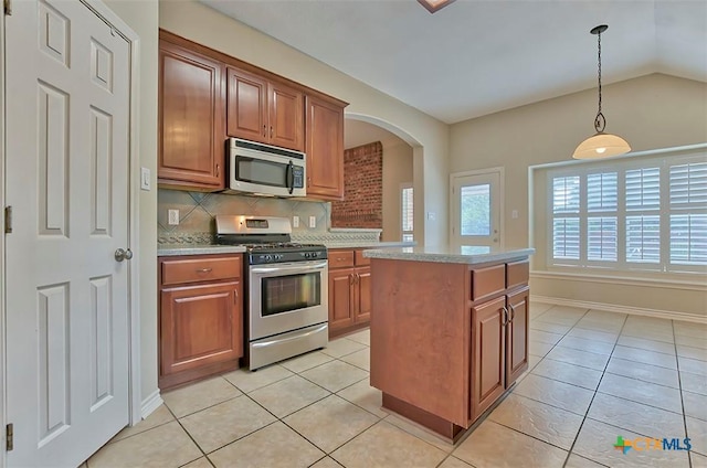 kitchen featuring lofted ceiling, a kitchen island, decorative backsplash, hanging light fixtures, and appliances with stainless steel finishes