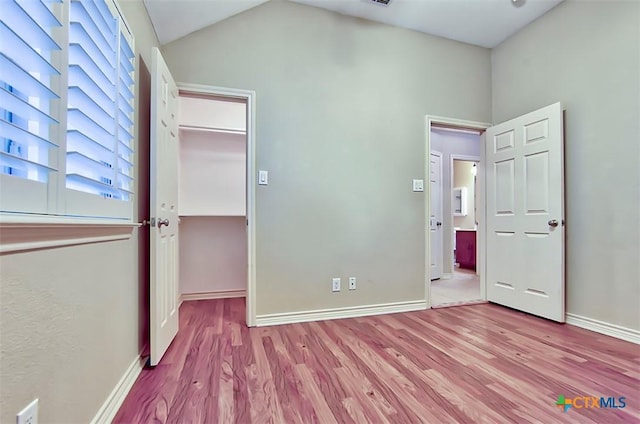 unfurnished bedroom featuring light wood-type flooring, a spacious closet, and a closet