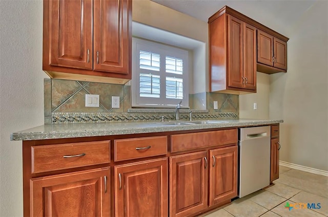 kitchen featuring tasteful backsplash, light tile patterned floors, dishwasher, and sink