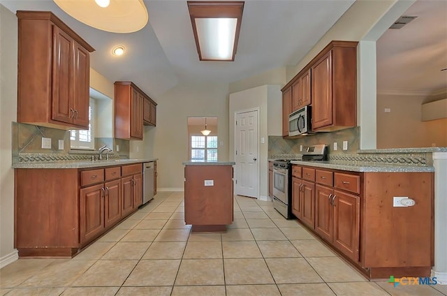 kitchen with decorative backsplash, sink, appliances with stainless steel finishes, and a kitchen island