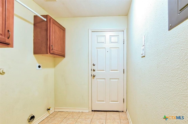 clothes washing area with light tile patterned floors, hookup for an electric dryer, and cabinets