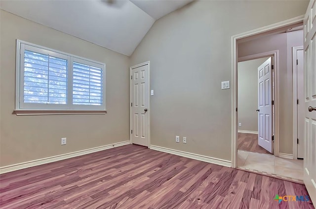 empty room featuring vaulted ceiling and light hardwood / wood-style flooring