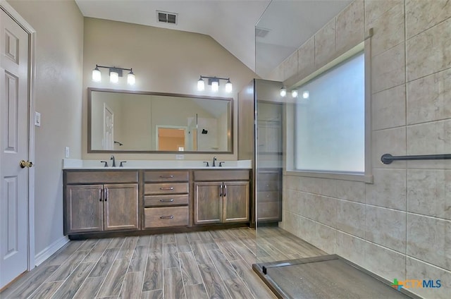 bathroom with lofted ceiling, walk in shower, and vanity