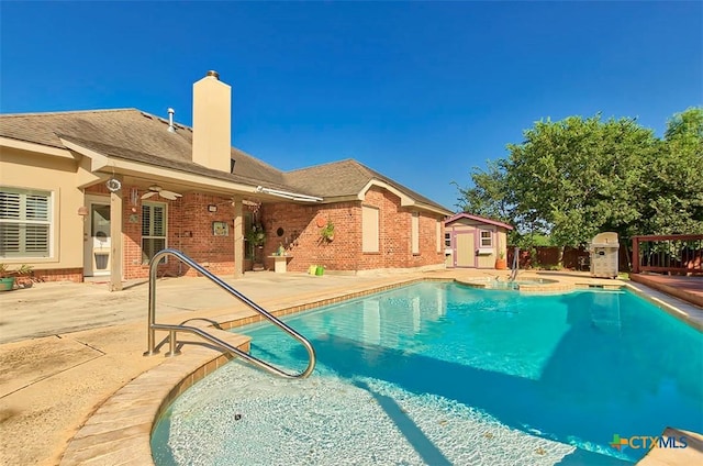 view of pool featuring a patio area, a jacuzzi, ceiling fan, and a storage unit