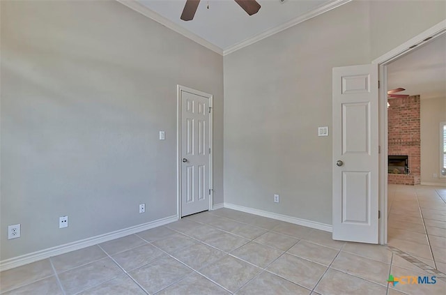 spare room with ceiling fan, light tile patterned floors, and a fireplace