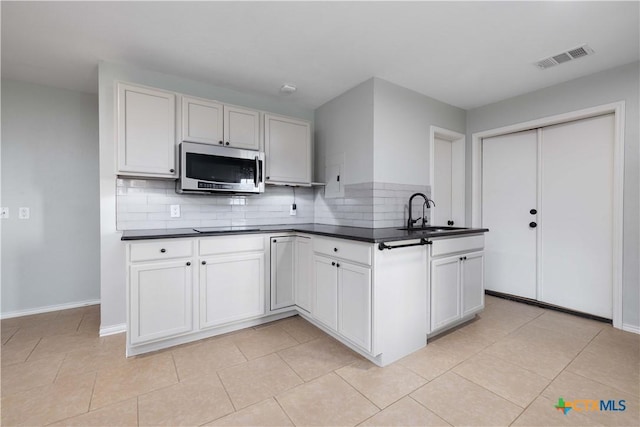 514 Eden Ranch Dr, Canyon Lake, TX 78133 - kitchen featuring stainless steel microwave, decorative backsplash, dark countertops, and light tile patterned flooring