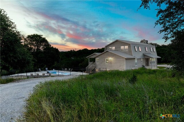 514 Eden Ranch Dr, Canyon Lake, TX 78133 - property exterior at dusk with an outdoor pool and a chimney