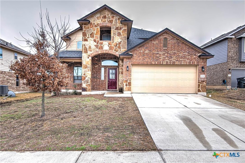 view of front of home with a garage and central AC