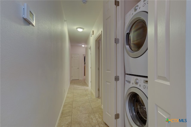 laundry room with stacked washing maching and dryer and light tile patterned floors