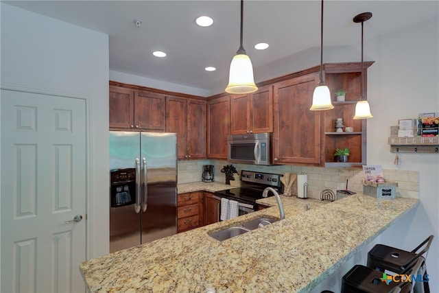 kitchen with kitchen peninsula, appliances with stainless steel finishes, hanging light fixtures, and tasteful backsplash