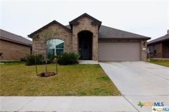 view of front facade featuring driveway, a front lawn, stone siding, and a garage
