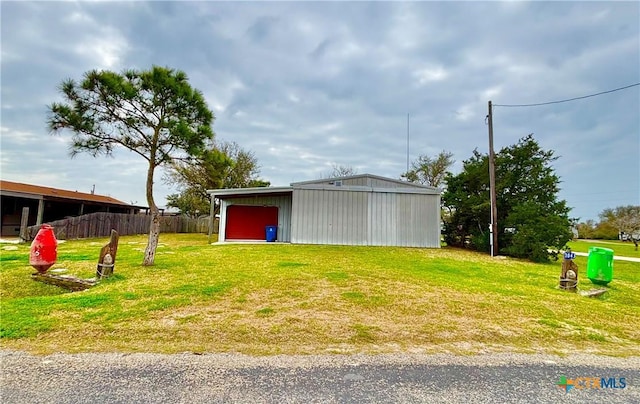 view of yard with an outbuilding, a pole building, fence, and a detached garage