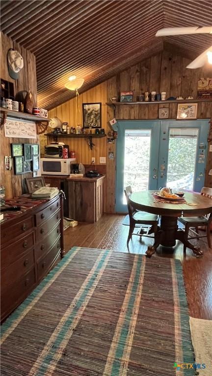 dining room featuring wooden walls, lofted ceiling, and hardwood / wood-style flooring