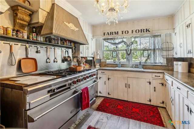 kitchen featuring sink, custom exhaust hood, white cabinets, light hardwood / wood-style floors, and a chandelier