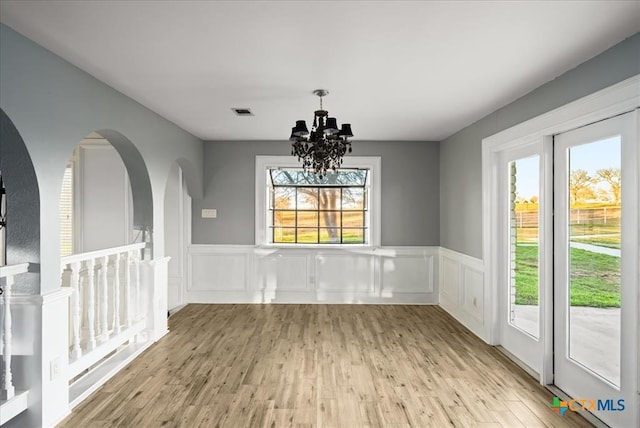 unfurnished dining area with a chandelier and light hardwood / wood-style flooring