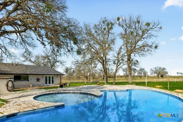 view of swimming pool with a yard and french doors