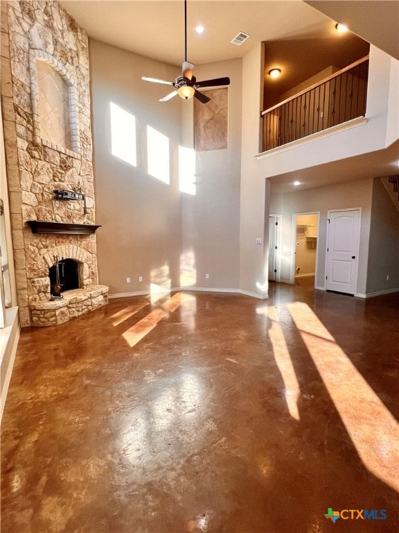 unfurnished living room with a fireplace, a towering ceiling, and ceiling fan